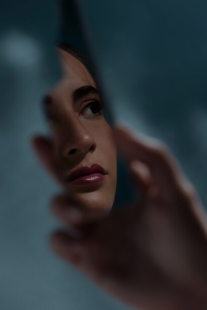 An unidentified woman holds a fractured mirror in a thought-provoking front view, symbolizing introspection and shattered reflections