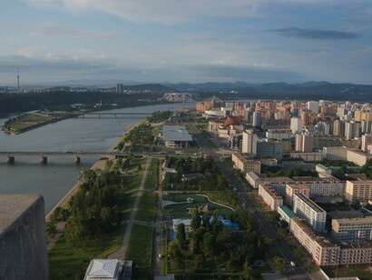 Uno scorcio mozzafiato della città lungo il fiume Taedong, con edifici moderni che si estendono fino all'orizzonte, riflettendo l'equilibrio tra natura e urbanizzazione, Pyongyang, Corea del Nord